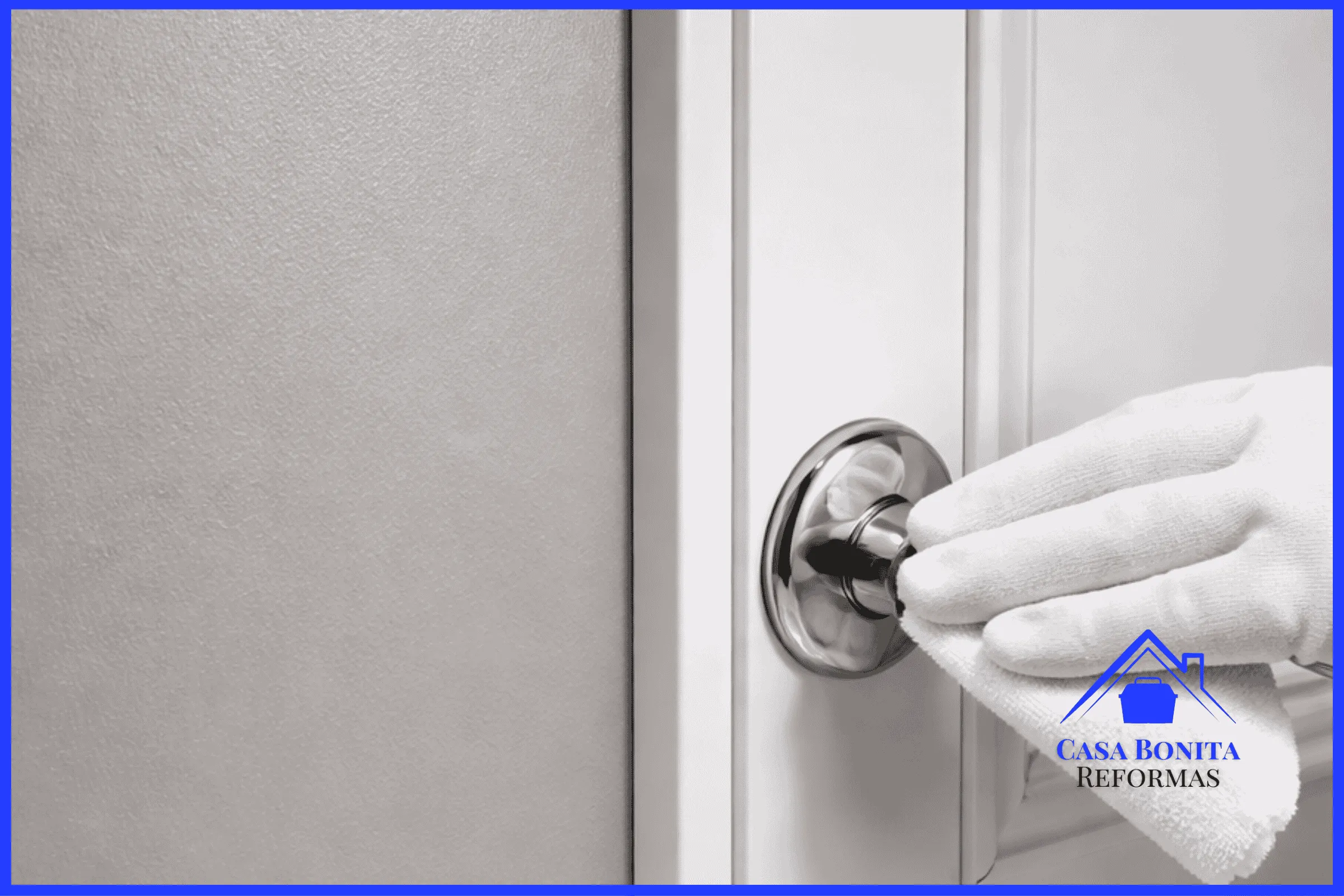 O Pós-Obra e a Entrega Chave na Mão parede recém-pintada (em um tom cinza acetinado sofisticado) e um rodapé branco de laca impecável. Uma mão usando uma luva branca de microfibra está passando suavemente sobre a maçaneta metálica brilhante de uma porta, fazendo o polimento final. Não há nenhuma marca de fita, pó de lixa ou pingo de tinta no chão de mármore logo abaixo. A iluminação destaca a textura lisa da parede e o brilho da limpeza extrema.