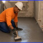 Pedreiro profissional aplicando argamassa polimérica em banheiro de apartamento em Salvador durante reforma residencial com impermeabilização conforme NBR 9575